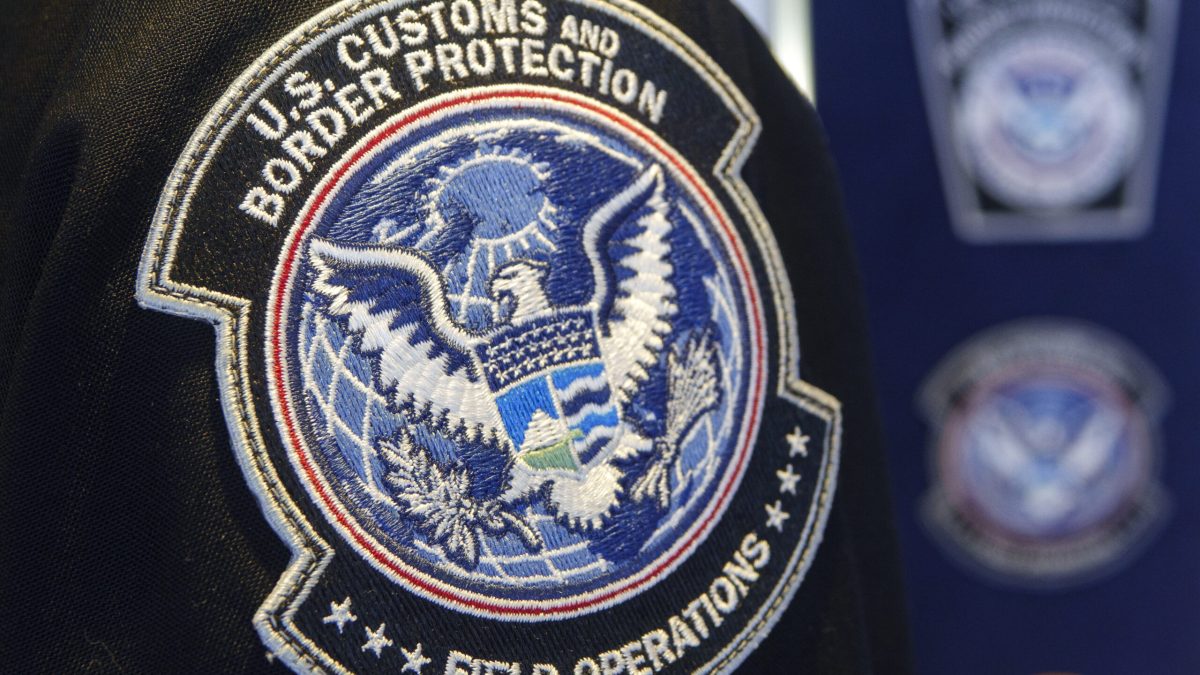 Traveler handing a smartphone to a customs officer at an airport terminal