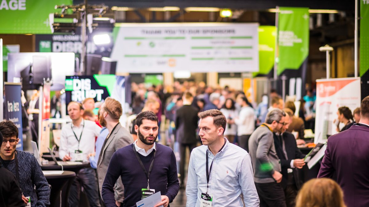 TechCrunch Disrupt conference expo hall with startup founders demonstrating products to investors