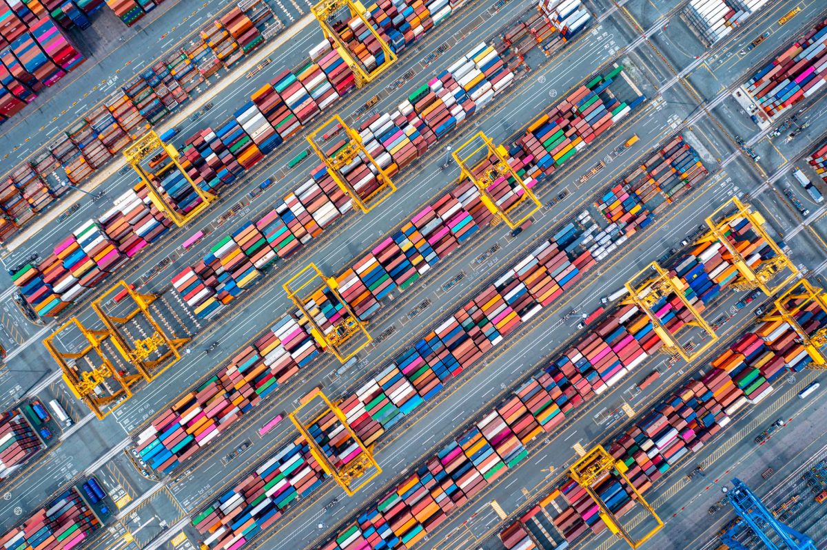 Container cranes loading cargo at a busy East Asian port at dusk