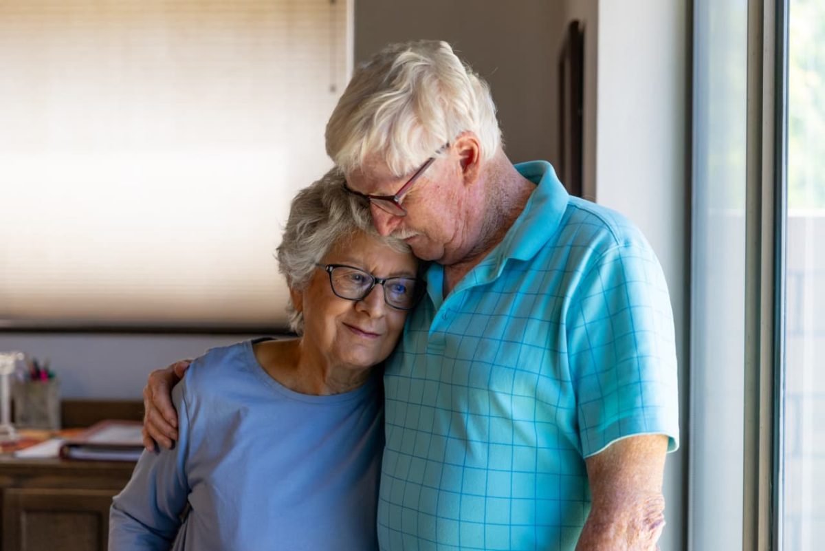 Elderly couple signing property documents while adult son watches in office