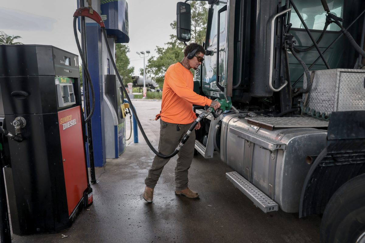 A shopper reviewing grocery receipts while pumping gasoline at a fuel station