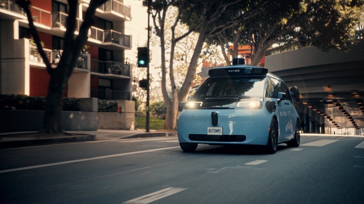 Waymo self-driving robotaxi with roof-mounted sensor array on city street