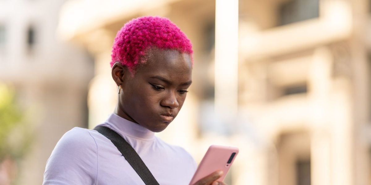Adult child sitting apart from mother on a park bench looking at phone