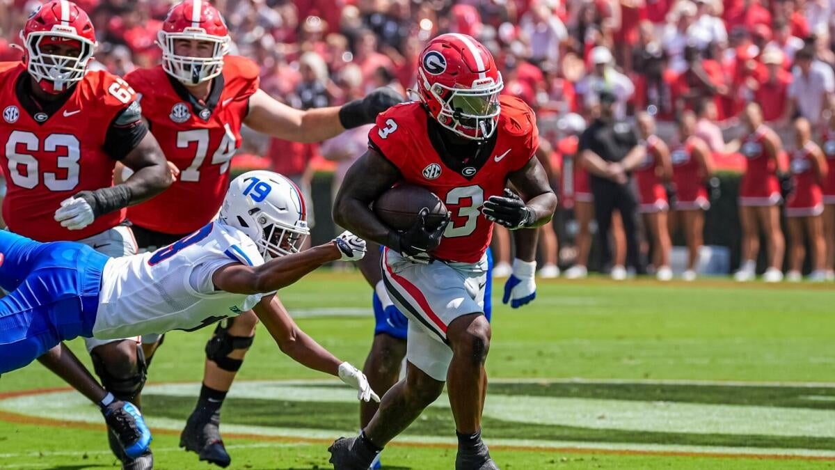 Georgia Bulldogs and Alabama Crimson Tide football players line up before a snap