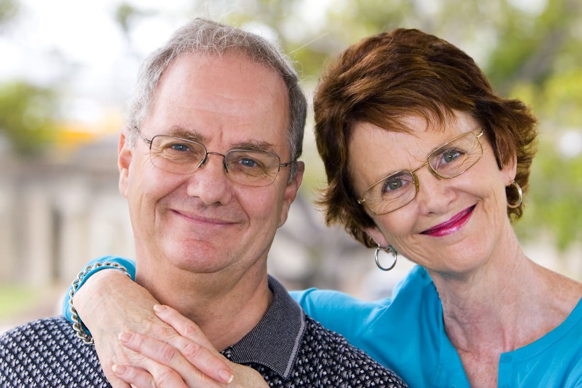 Elderly couple reviewing retirement savings and travel budget at kitchen table