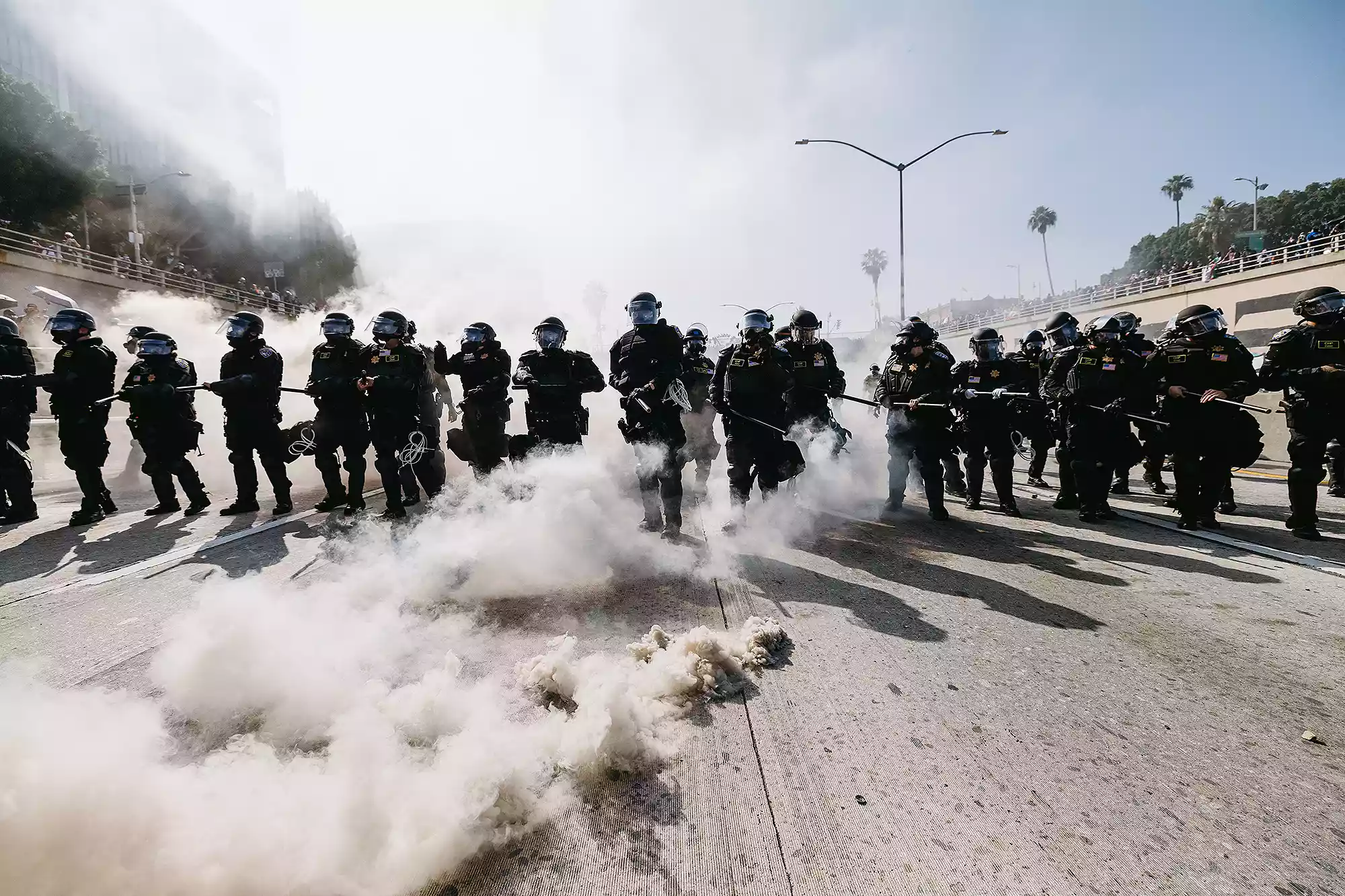 Smoke fills the air as law enforcement officers in riot gear advance during protests in Los Angeles, California, on June 8, 2025. Following a series of aggressive federal immigration operations in Los Angeles, tensions escalated when Immigration and Customs Enforcement (ICE) agents conducted a high-profile raid on a Home Depot location. The raid sparked widespread protests across the city, where demonstrators decried the targeting of immigrant communities and the separation of families. Clashes soon broke out between protesters and federal agents, prompting U.S. President Donald Trump to deploy 2,000 National Guard troops to the city, a move harshly criticized by California officials, including the governor, as "purposefully inflammatory."